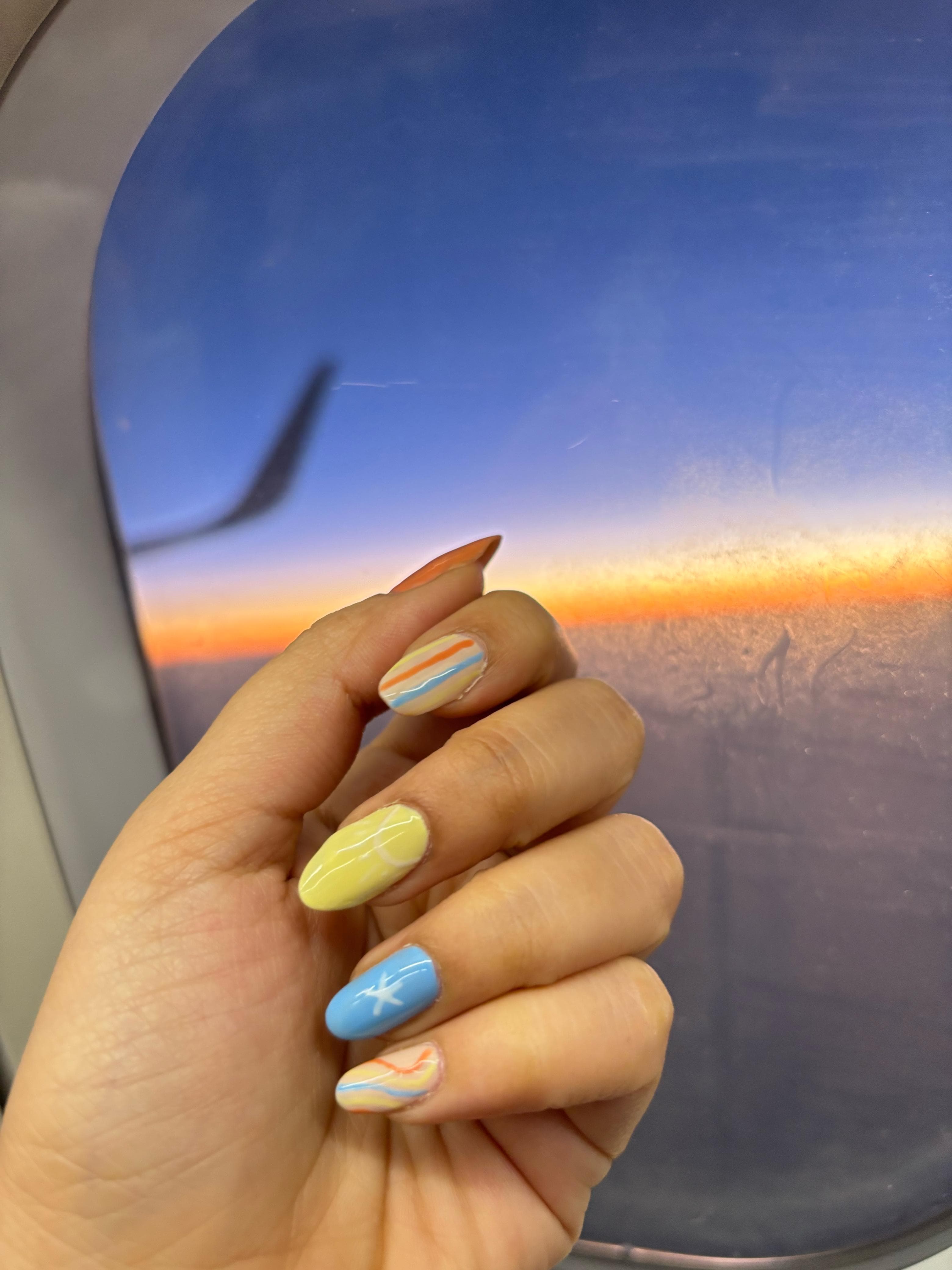 Pastel travel-inspired nail art captured at golden hour by a window